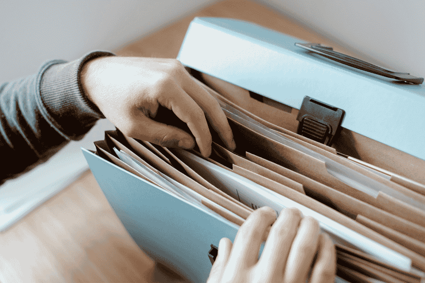 Pessoa organizando pastas e documentos em arquivo, simbolizando a importância de guardar a carta de quitação de dívida e outros comprovantes de pagamento.