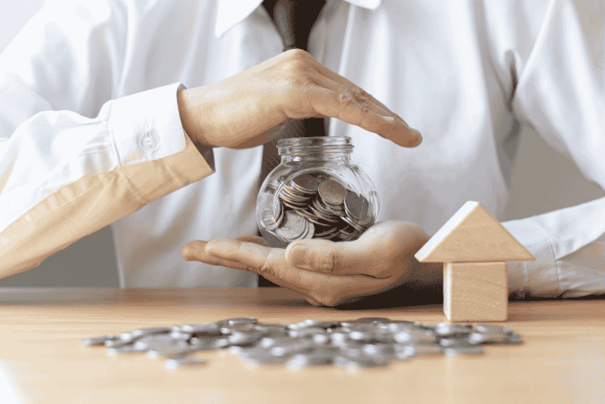 Homem guardando moedas em pote de vidro simbolizando disciplina financeira e construção de uma vida próspera ao sair do vermelho.