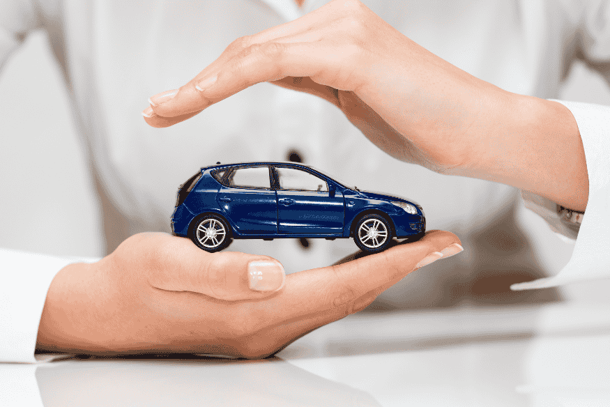 Mãos protegendo um carro em miniatura, representando segurança e planejamento na compra de veículo por meio de consórcio.