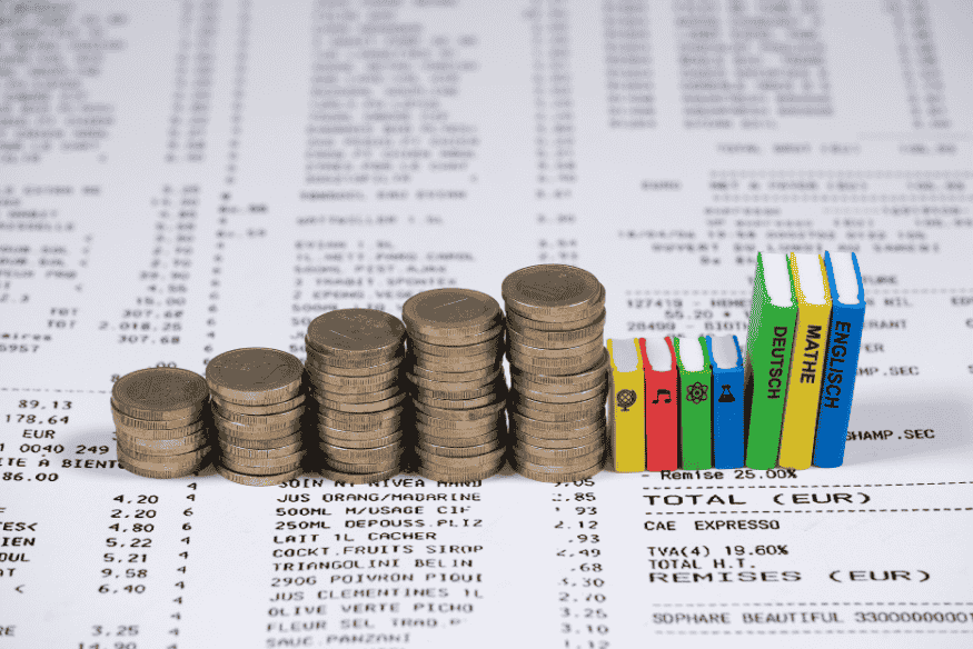 Portabilidade de dívida representada por pilhas de moedas e livros, simbolizando economia financeira e conhecimento para reduzir custos de empréstimos.